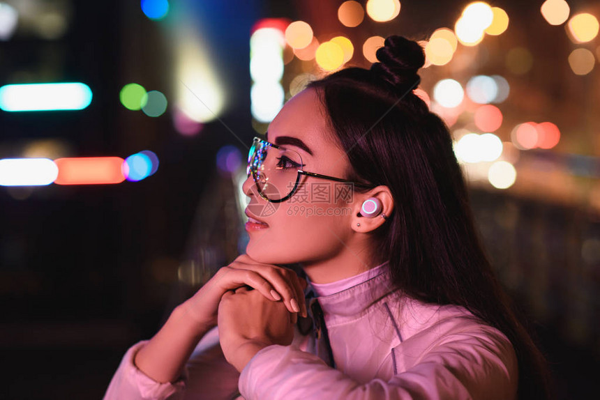 时尚的年轻女孩身戴眼镜和无线耳机图片