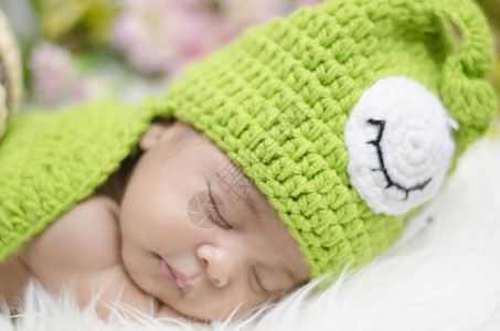穿着编织的蜗牛服装睡在白毯子上睡觉的甜蜜图片