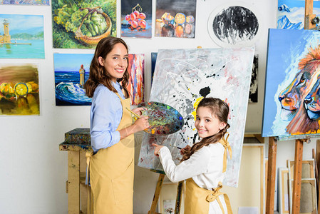 教师和学生在艺术学校车间的画布旁站立图片
