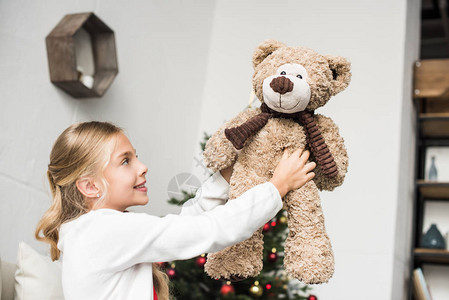 快乐可爱的小孩抱着泰迪熊坐在圣诞图片