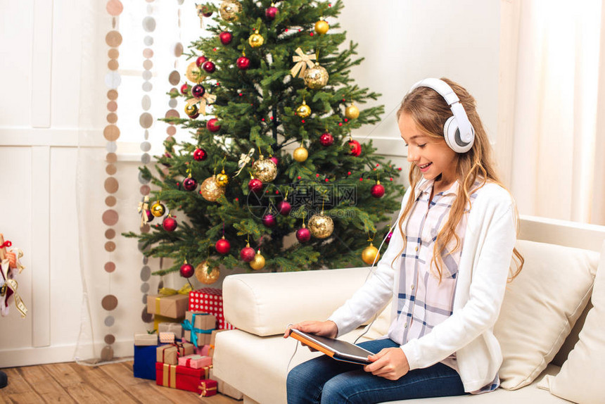 在圣诞节前夕使用数字平板的耳机用耳机装着美丽的图片