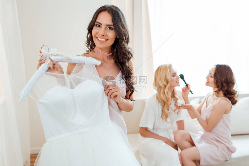 美丽的新娘拿着婚纱新娘而伴图片