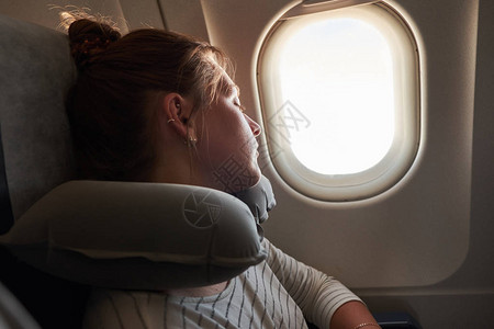 一个在飞机上睡觉的年轻女孩乘客睡在飞机上航程高清图片素材