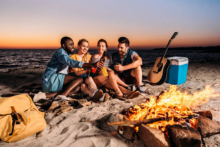 快乐的多民族朋友在日落时分在沙滩上共度时光图片