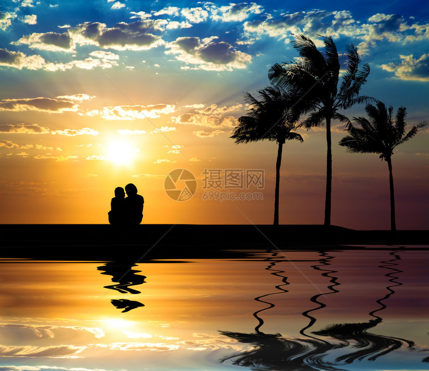 情侣在沙滩上看日落的剪影图片