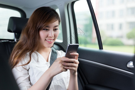 乘坐汽车使用手机的美丽的亚洲图片