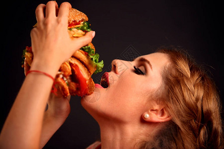 女人吃汉堡学生吃快餐女孩张开嘴咬汉堡女孩试图吃巨型三明治在黑色背图片