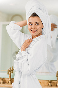 穿着浴袍和头戴毛巾的美丽笑美女孩在洗图片