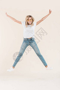 快乐的年轻女子在眼镜中与高举的手臂跳跃图片