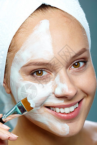 新鲜女人用刷子将面膜敷在脸上图片