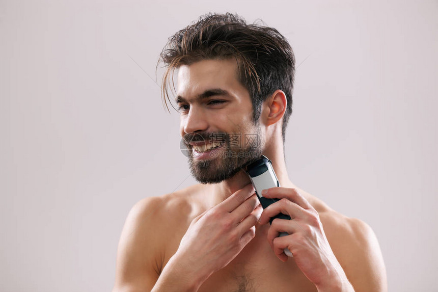 年轻人正在用电动剃须刀刮胡子图片