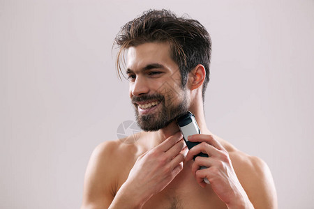 年轻人正在用电动剃须刀刮胡子图片