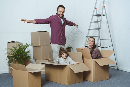 搬家时用纸板箱玩得开心的幸福家庭图片