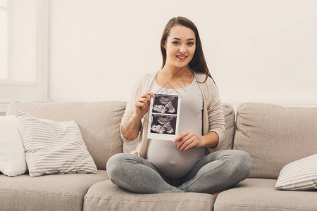 快乐的期待女士享受她未出生孩子的第一张照片背景图片