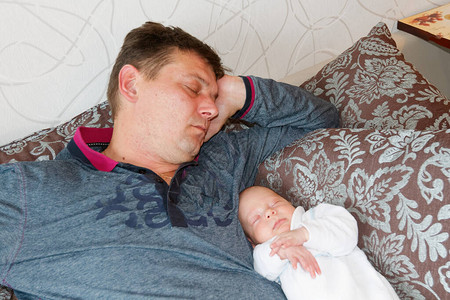 父亲和儿子婴儿在沙发上睡累了图片