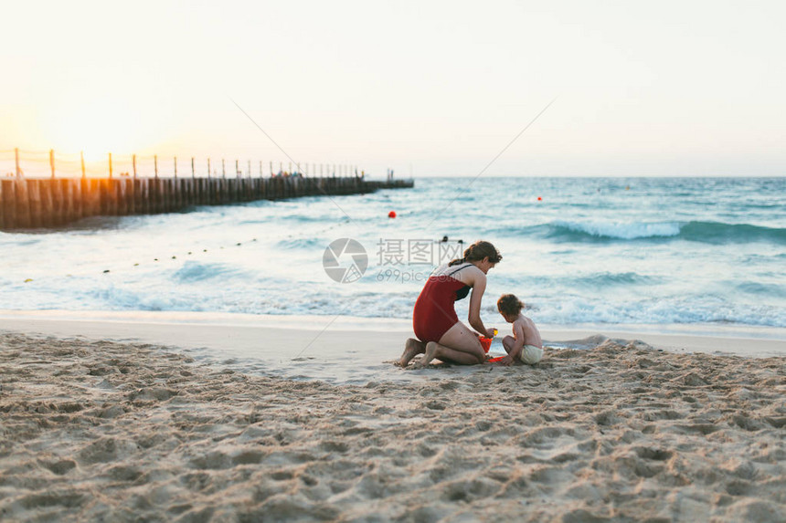 可爱的女婴和年轻母亲在海边与沙滩一图片
