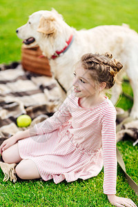 可爱笑的小女孩在野餐时与狗一起休息图片