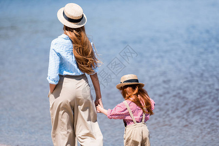 年轻母女牵手走在海边的背影图片