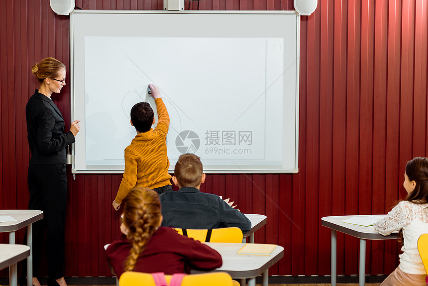 课程期间男孩在交互式白板上写图片