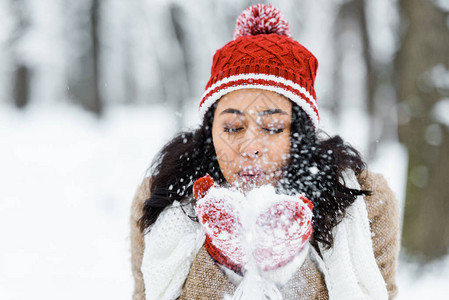 在冬季森林公园吹雪的美籍女子图片