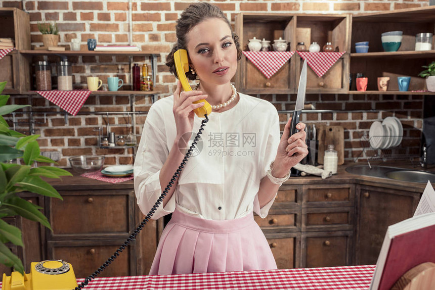 厨房用黄色有线电话用刀说话的成年严重图片