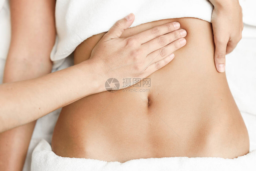女腹部按摩手术师对腹部施压在温泉理发店接受图片