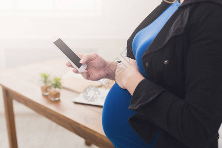 面目全非的孕妇拿着有黑屏的智能手机准女商人使用手机触摸腹图片
