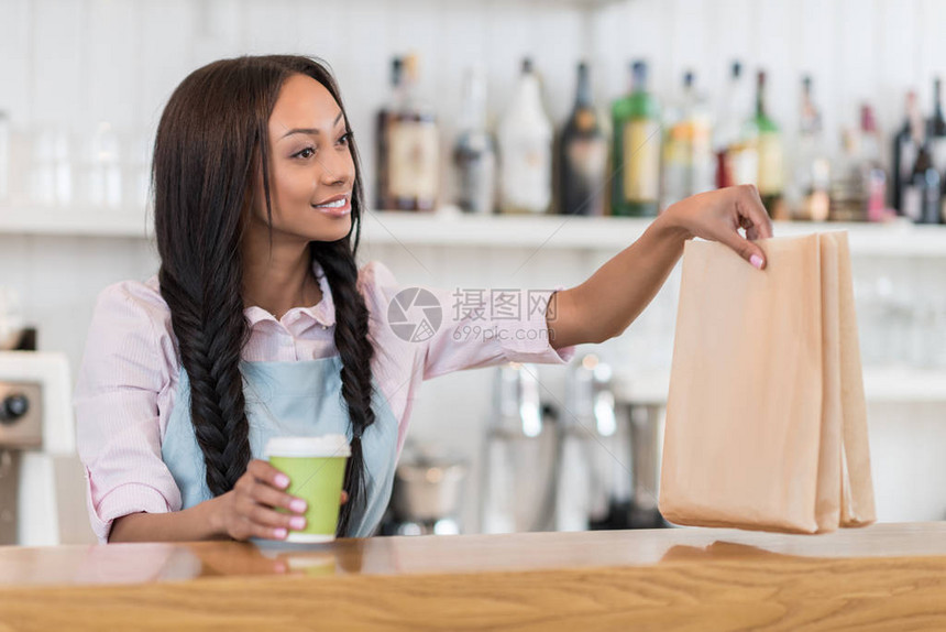 微笑的美国黑人女服务员拿着咖啡去拿图片