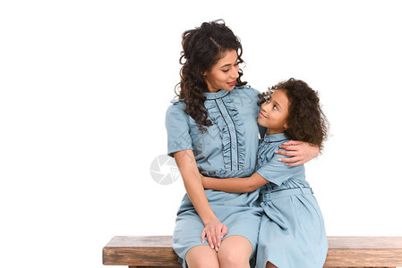 母亲和女儿坐在白板上独自坐着时拥抱自图片