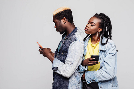 女人试图看到男人在电话里聊天非洲夫妇的侧面肖像背靠将手机图片