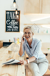 快乐的成熟女人手持报纸在咖啡馆用背景图片