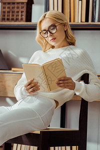 戴眼镜坐在椅子上看书的成年图片