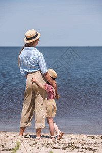 母亲和女儿背着草帽的眼神在海边图片