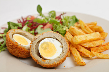 苏格兰鸡蛋用面包香肠肉包裹并油炸的煮熟的鸡蛋配以薯条图片
