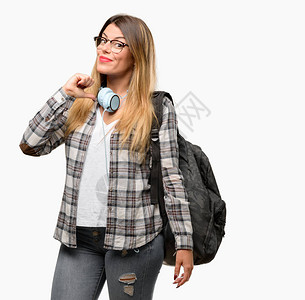 手持耳机和背包的年轻女学生带着耳机图片