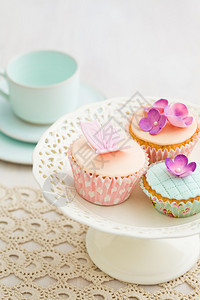 用粉红色糖花和糖蝴蝶装饰的纸杯蛋糕图片