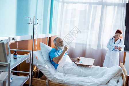 坐在医院床上和在医生做笔记时吃药的图片