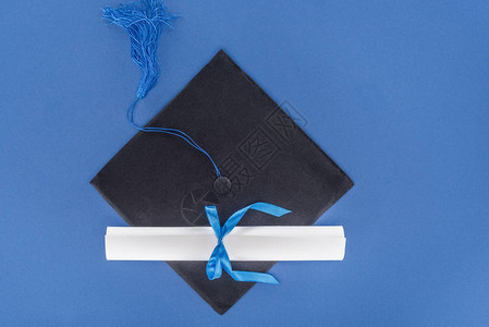 毕业帽子和毕业文凭蓝丝图片