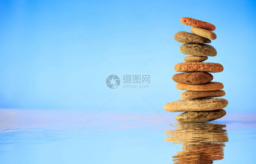 蓝色背景上堆积的禅石水面上的倒影图片