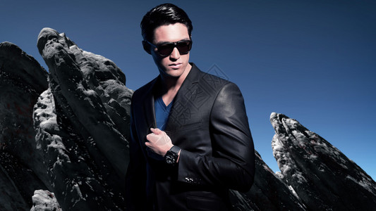 穿着灰色西装和黑墨镜的亚洲男子冬季时尚风气外面冬天岩石背景图片