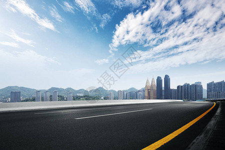 空旷的柏油路与蓝天下的市容背景图片