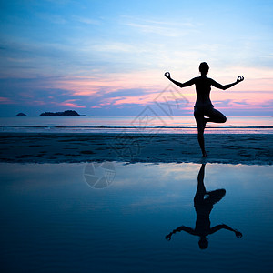 日落后在沙滩上练习瑜伽的女人图片