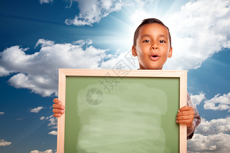 骄傲的西班牙裔男孩在蓝天和白云上与SunBurs图片