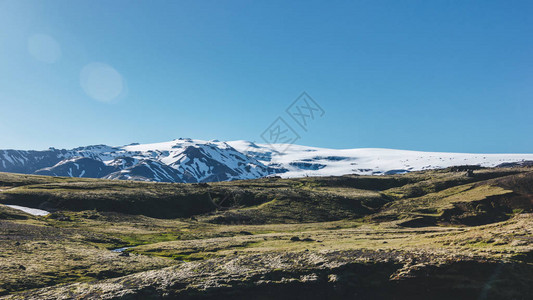 冰岛的明蓝天空下积雪覆盖着山图片