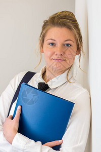 穿着校服的学生拿着蓝色文件站在学校制服里图片