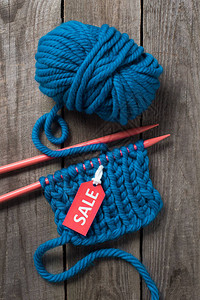 蓝色编织针头蓝色毛线球和木制背景销售标图片