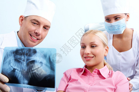 一名有牙医的妇女的肖像在助理背后展示她图片