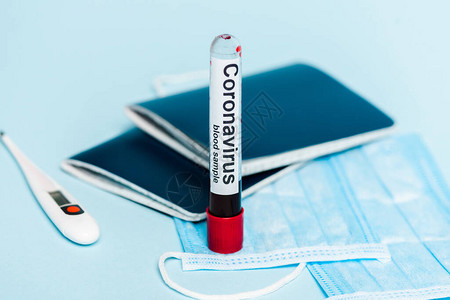 血样和冠状在医疗面罩温度计和蓝底护照上贴有血样的测试管选择焦点图片