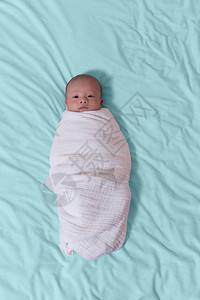 婴儿男孩被蒙在白毯上图片