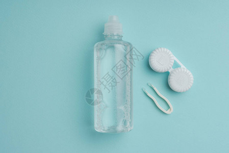 瓶tweezers和蓝色桌面隐形眼镜容器中的无菌液背景图片